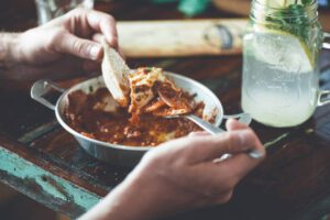 Man eating omelet with tomato sauce and piece of bread from pan